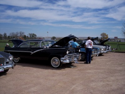 1972 Ford Ranchero - Several classic cars are displayed with hoods open under a partly cloudy sky.