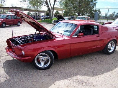 1972 Ford Ranchero - A shiny red 1967 Ford Mustang coupe is displayed with its hood open, revealing the engine bay.