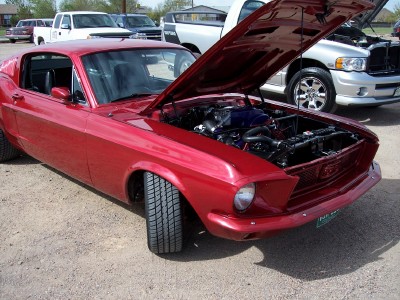 1972 Ford Ranchero - Classic red coupe with its engine exposed, parked outdoors with other vehicles.