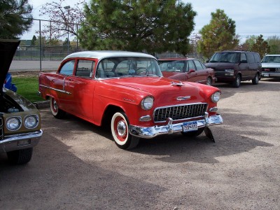 1972 Ford Ranchero - A red and white 1955 Chevrolet sedan is parked outdoors with other vehicles.