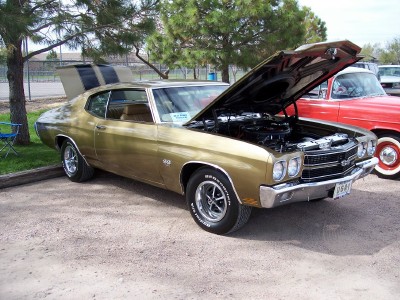 1972 Ford Ranchero - A gold 1970 Chevrolet Chevelle SS is parked with its hood open, displaying its engine bay.