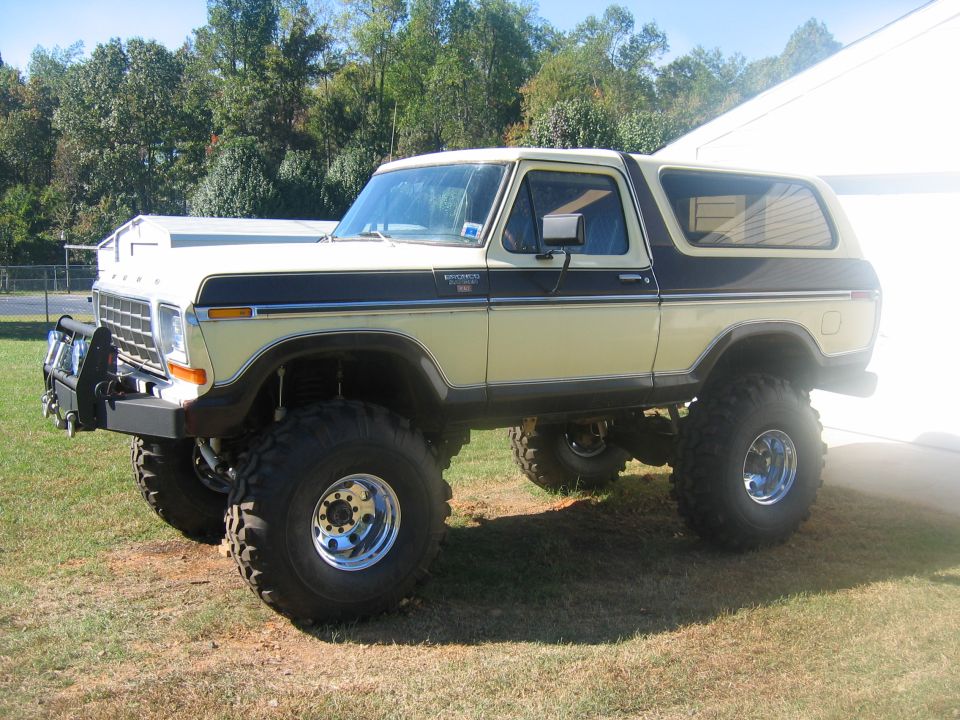 Lifted 1978 Ford Bronco with custom bumper and large tires, parked on grass