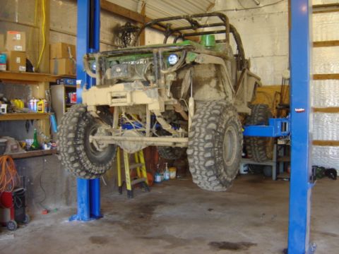 1992 Ford Bronco - A heavily modified Suzuki Samurai is raised on a car lift inside a workshop.