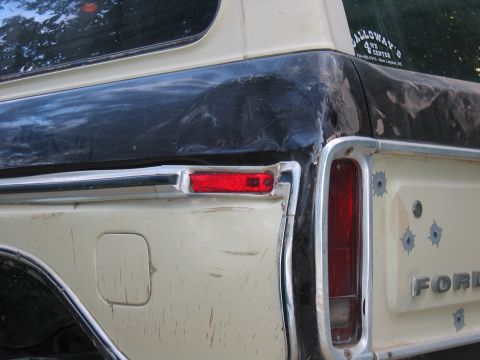 1992 Ford Mustang - This Ford truck has a dented rear panel with several bullet holes and a visible 'FORD' emblem.