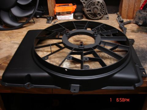 1979 Ford Bronco - A black plastic radiator fan shroud is shown on a wooden surface, with other automotive parts visible.