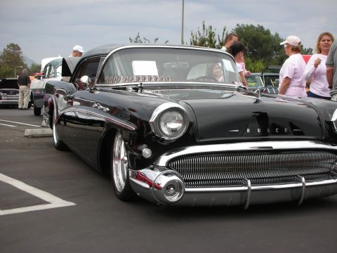 1992 Ford Crown Victoria - A classic black Buick is displayed at a car show with people milling around.