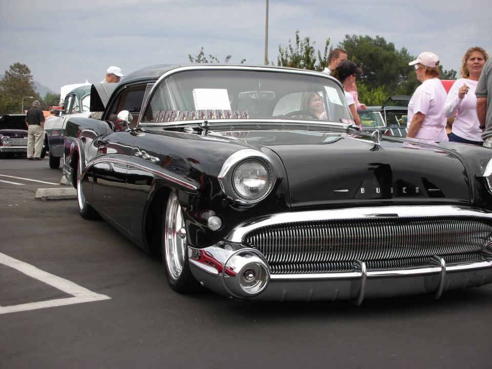 Black Buick with chrome grille and headlights, parked at an outdoor car show