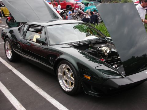 1992 Ford Crown Victoria - A dark green sports car with its hood open, revealing the engine and custom wheels.
