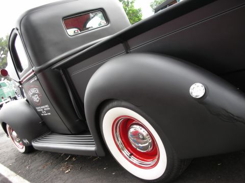 1992 Ford Crown Victoria - A classic black pickup truck with custom red wheels and whitewall tires is parked outdoors.