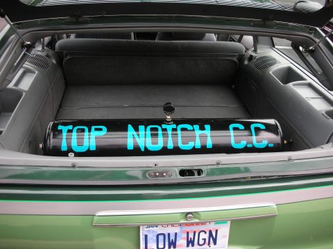 1992 Ford Crown Victoria - The trunk of a green vehicle contains a black air tank with blue lettering that reads "TOP NOTCH C.C."