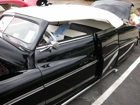 1992 Ford Crown Victoria - A black convertible with a white top is parked next to a red car, with a person by the open trunk.