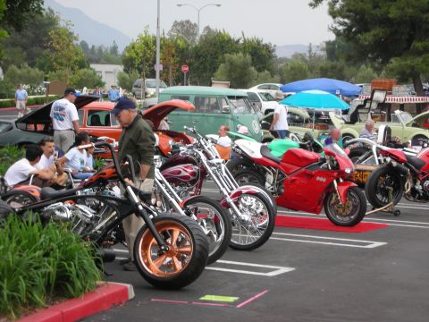 1992 Ford Crown Victoria - A variety of motorcycles and cars are displayed at an outdoor car show, with people milling around.