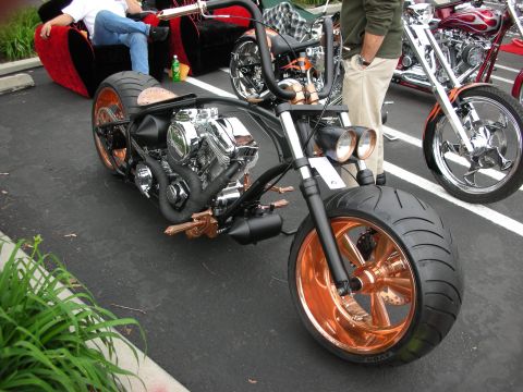1992 Ford Crown Victoria - A custom chopper motorcycle with striking copper accents and a powerful engine is displayed at an outdoor event.