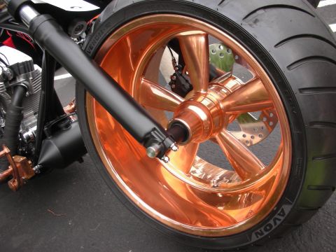 1992 Ford Crown Victoria - A custom motorcycle features a striking copper-finished wheel and tire, with a black suspension fork in view.