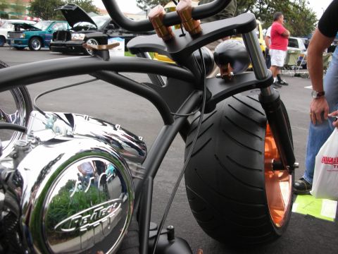 1992 Ford Crown Victoria - Custom motorcycle with a prominent chrome engine and copper accents on the wheels and handlebars is displayed at a car show.