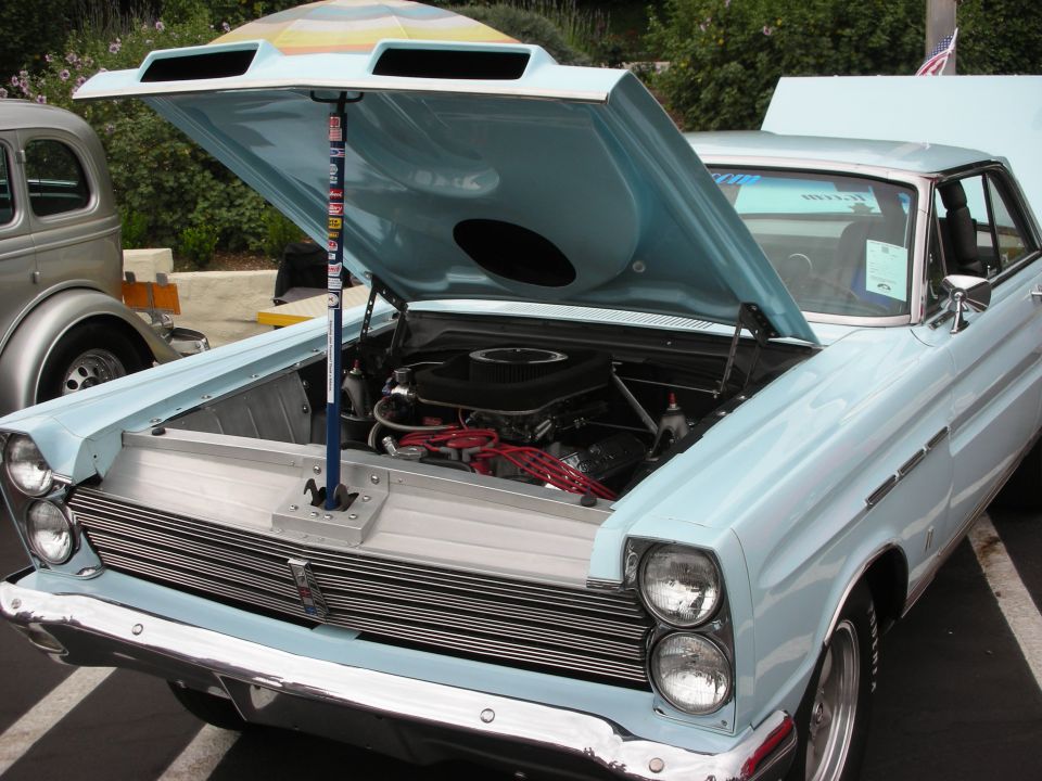 Light blue 1965 Mercury Comet with hood open, showing engine and chrome grille