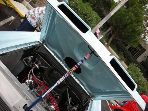 1992 Ford Crown Victoria - A light blue car's engine bay is visible with the hood open, displaying the engine and a decorative rod.