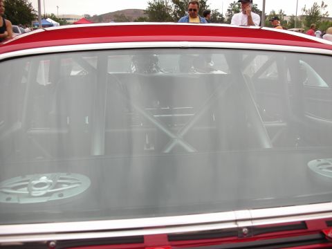 1992 Ford Crown Victoria - The interior of a red car, showing a roll cage and speakers through the rear window.