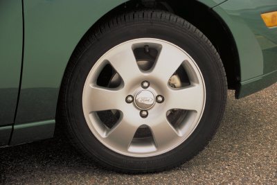 2002 Ford Focus - Close-up of a green car's wheel, showing the silver rim with the Ford emblem and a portion of the fender.