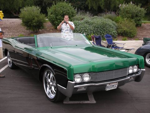 1992 Ford Crown Victoria - A man photographs a two-tone convertible with a prominent grille and dual headlights.