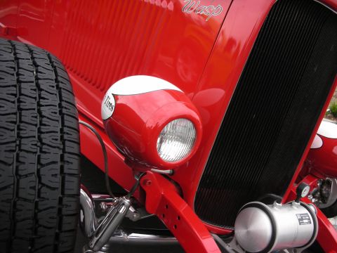 1992 Ford Crown Victoria - Close-up of a red hot rod's front end, showing a spare tire and a distinctive headlight.