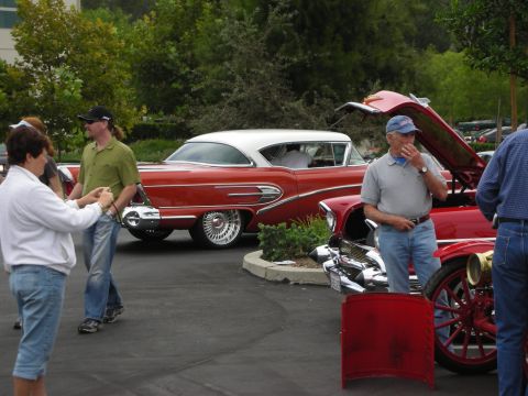 1992 Ford Crown Victoria - Two vintage automobiles are displayed at an outdoor car show, with people admiring them.