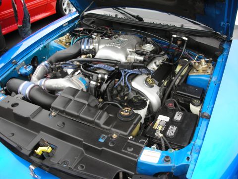 1992 Ford Crown Victoria - The engine bay of a blue 1996 Ford Mustang GT, modified with a turbocharger, is visible.