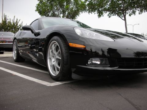 1992 Ford Crown Victoria - Front corner view of a black Chevrolet Corvette C6 with aftermarket wheels.
