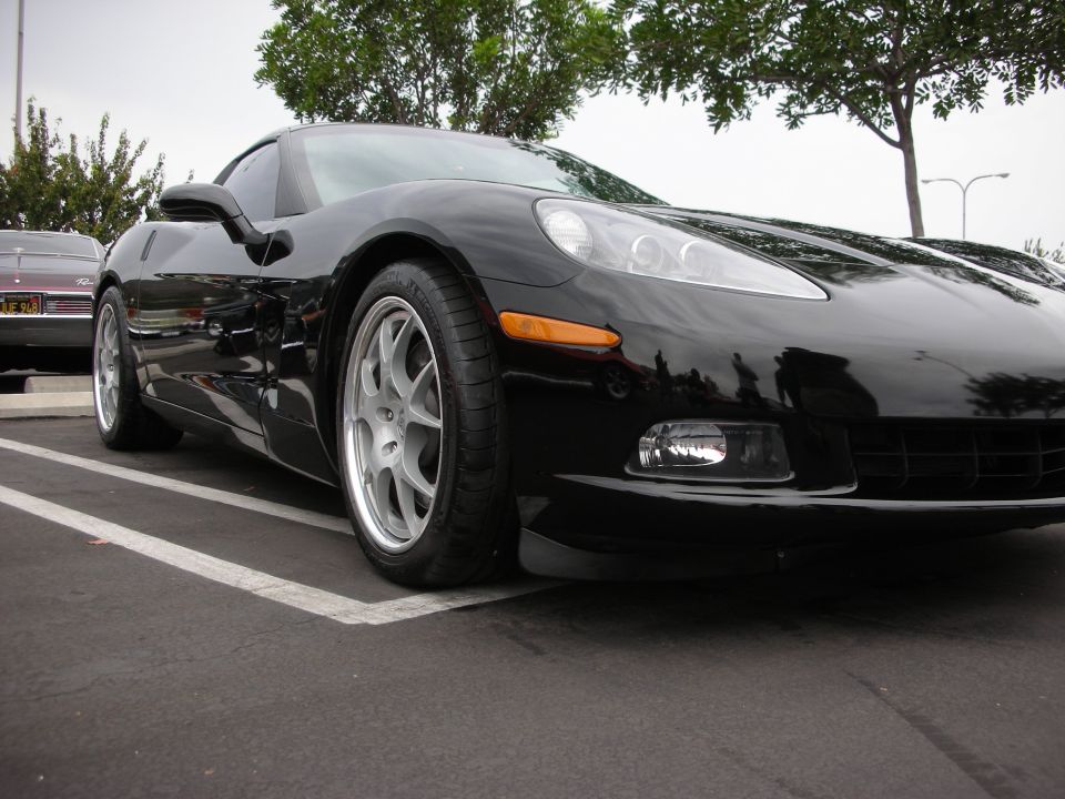 Black Chevrolet Corvette C6 parked in a lot, another car visible behind it