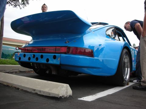 1992 Ford Crown Victoria - A blue Porsche 911 race car is parked, with onlookers examining its distinctive rear spoiler and bumper.