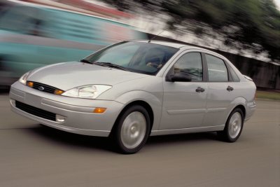 2002 Ford Focus - A silver sedan is captured in motion on a paved road, with a blurred background suggesting movement.