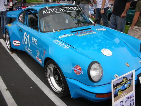 1992 Ford Crown Victoria - A bright blue Porsche race car, number 61, displays various sponsor decals and a "Porsche Owners Club" sticker.