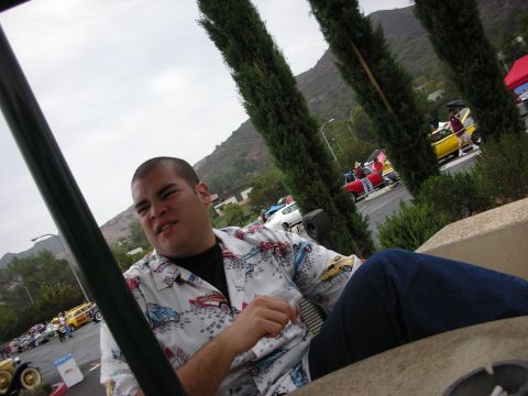 1992 Ford Crown Victoria - A man is seated at what appears to be an outdoor event with multiple cars visible in the background.