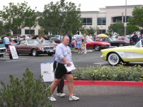 1992 Ford Crown Victoria - Attendees stroll through a car show various vintage automobiles on display.
