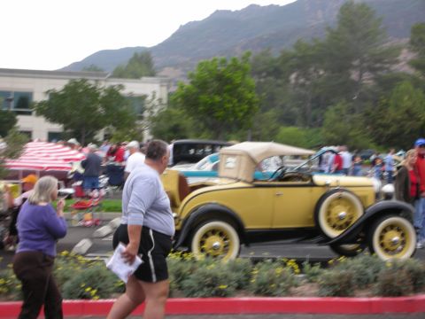 1992 Ford Crown Victoria - A yellow convertible with a tan top is parked at a car show with people around.