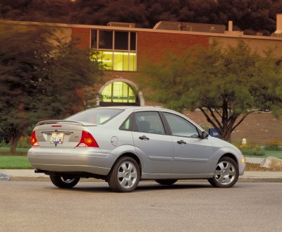 2002 Ford Focus - Rear view of a silver 2002 Ford Focus sedan, showing its taillights and rear bumper. The vehicle is parked on a street in front of a buildi…