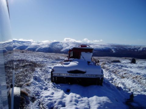 2000 Ford E350 - A tracked vehicle sits covered in snow in a vast, mountainous winter landscape.