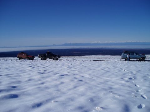 2000 Ford E350 - Several SUVs are parked in a snowy landscape with mountains in the distance.