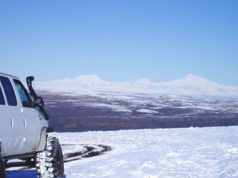 2000 Ford E350 - A white van equipped with a snorkel and tires sits in a snowy landscape, with snow-capped mountains visible in the distance under a clear b…