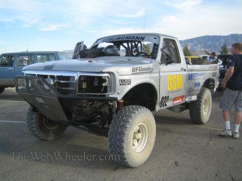 1990 Ford Bronco - silver Ford off-road race truck numbered 822 with DSM, BFGoodrich and Schlingmann livery on a tube bumper, parked on pavement.