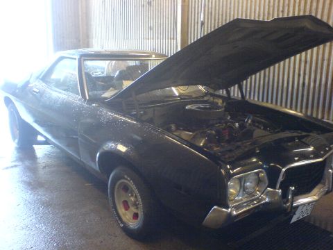 1972 Ford Ranchero - A black 1972 Ford Ranchero sits in a garage with its hood open, revealing the engine compartment.