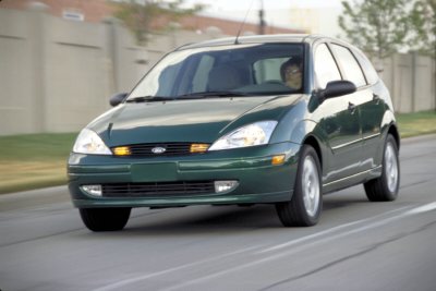 2002 Ford Focus - A green Ford Focus hatchback is shown driving on a road with a driver visible inside.