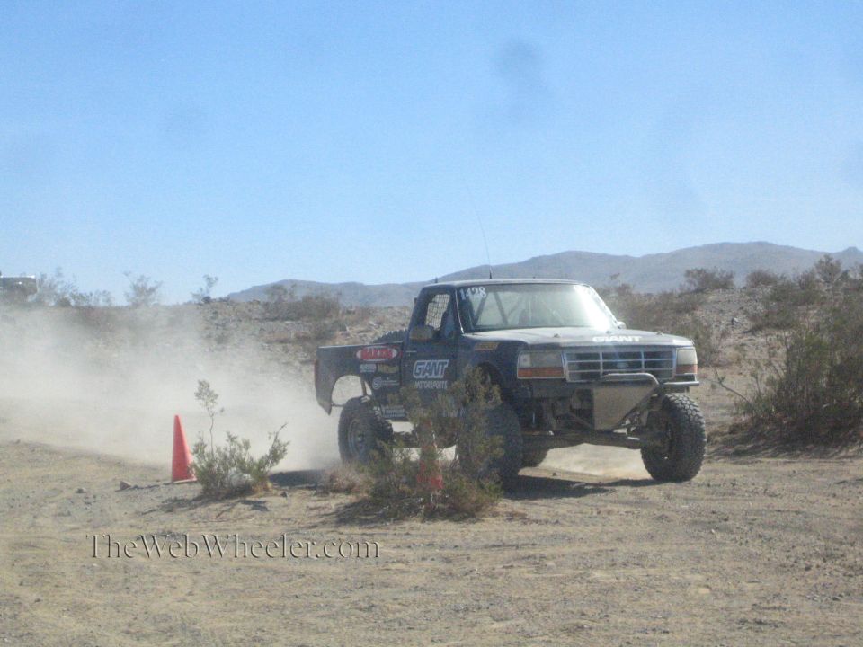 Dark Ford off-road truck front view raising dust in the desert
