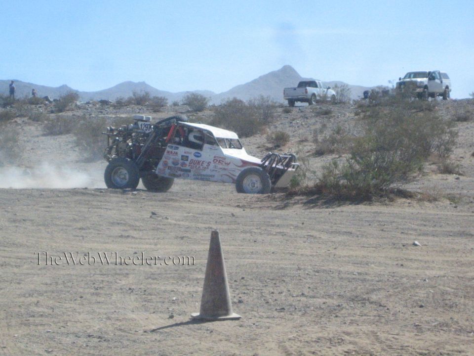 White off-road buggy with exposed engine sliding across the desert