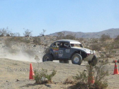 1990 Ford Bronco - Baja-style Volkswagen Beetle race car numbered 509 corners through a rocky desert course marked by traffic cones.