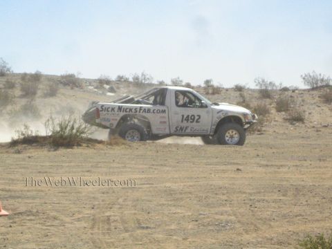 1990 Ford Bronco - white off-road race truck numbered 1492 with SickNicksFab.com livery races across a dusty desert course.