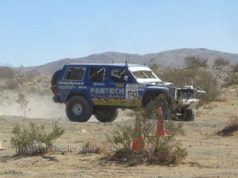 1990 Ford Bronco - blue Fabtech and JeepSpeed liveried race SUV numbered 1743 runs a desert course past traffic cones.