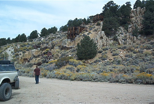 Person and truck on dirt road below old mine ruins