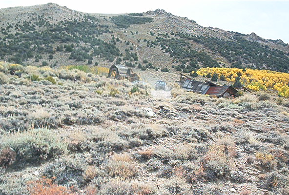 Vehicle near old wooden structures on desert mountain