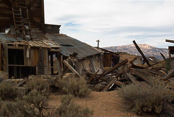 Dilapidated wooden structures in a desert landscape with mountains in the background